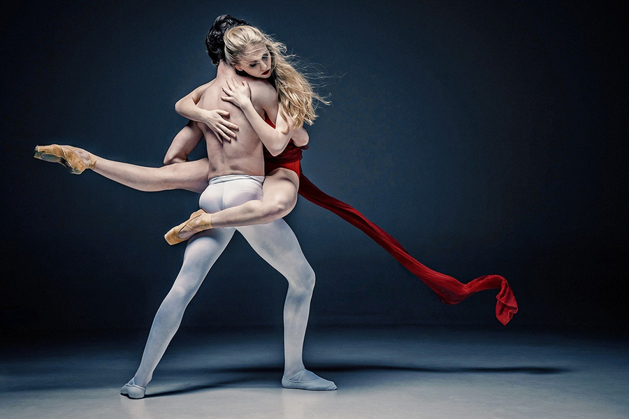 Image d'en-tête de l'article Je Réalise " La communication : secret d'un couple uni ", sur laquelle l'on voit, sur fond noir et sur scène, un danseur classique en legging blanc tenant dans ses bras une femme, danseuse classique blonde serrée contre lui, en habit bordeaux, avec une traîne.